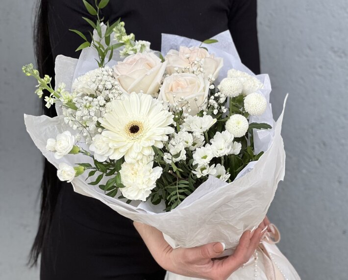 Белоснежный букет цветов, в состав которого входят ароматные, пионовидные розы сорта Вайт Охара, маттиола, гербера, диантус, несколько видов хризантем, шабо и зелень